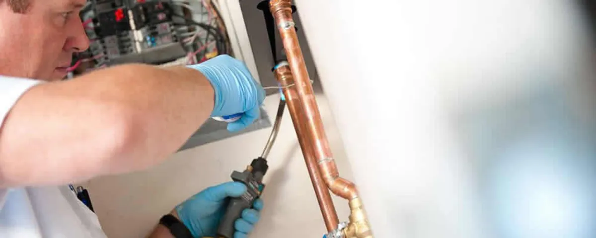Water heater repair technician testing copper pipe connections and controls in Evansville, IN